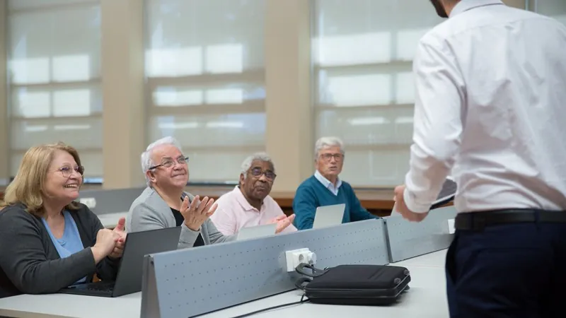 Turma de adultos em aula prática de inteligência artificial, cada um com seu notebook