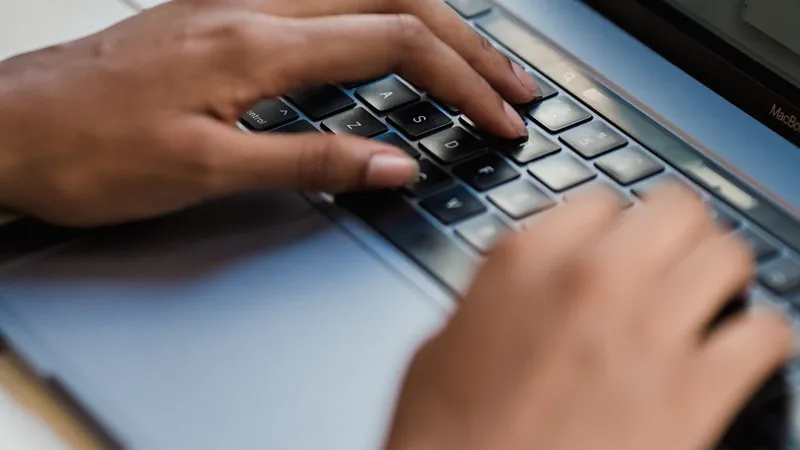 Mãos digitando um pedido para a inteligência artificial no teclado do notebook