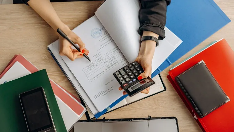 Mesa do financeiro com calculadora, cadernos e documentos de fechamento