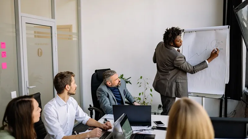 Treinamento in company: equipe reunida em sala com apresentação no quadro