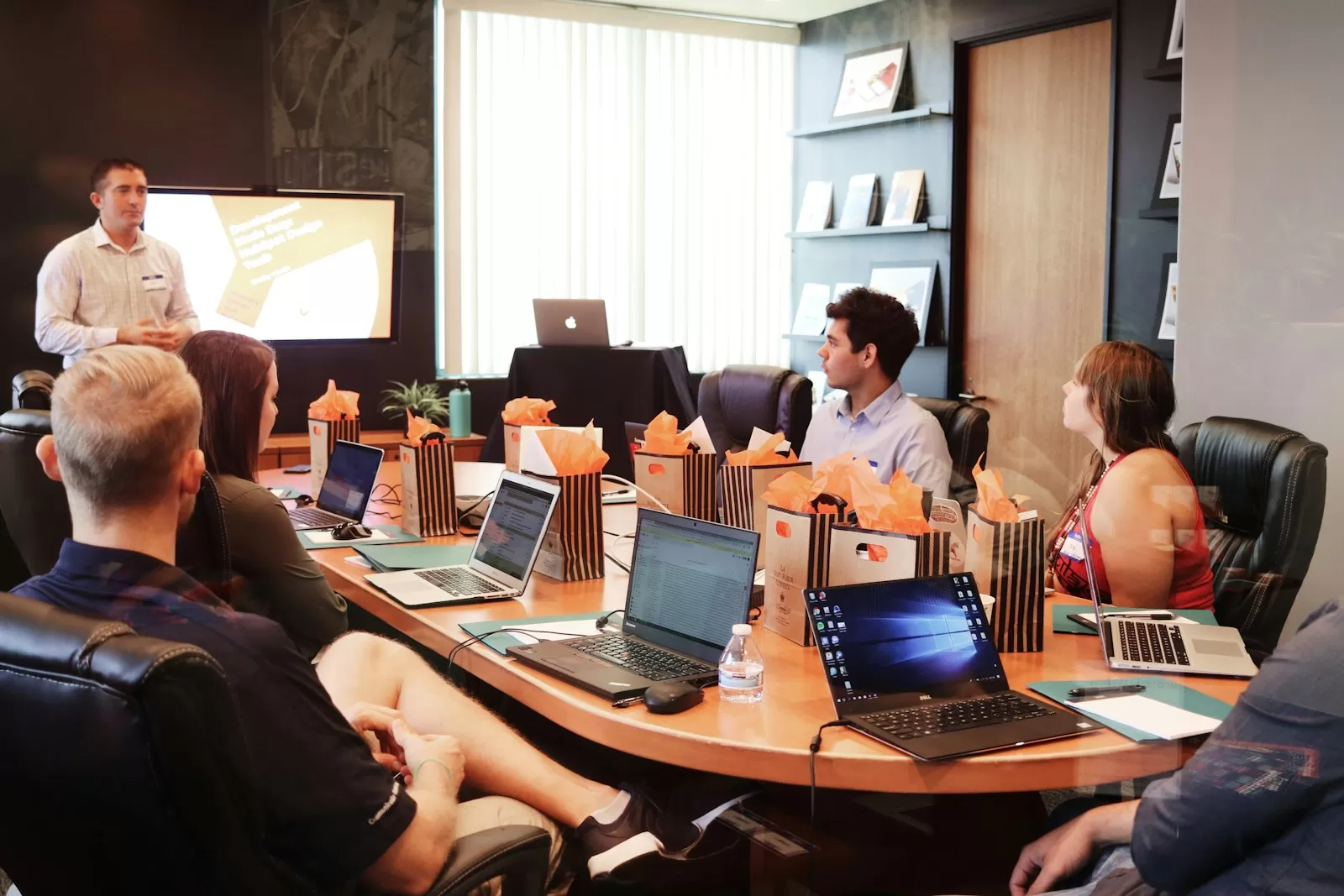 Profissional apresentando resultados para a equipe em uma reunião de trabalho com laptops
