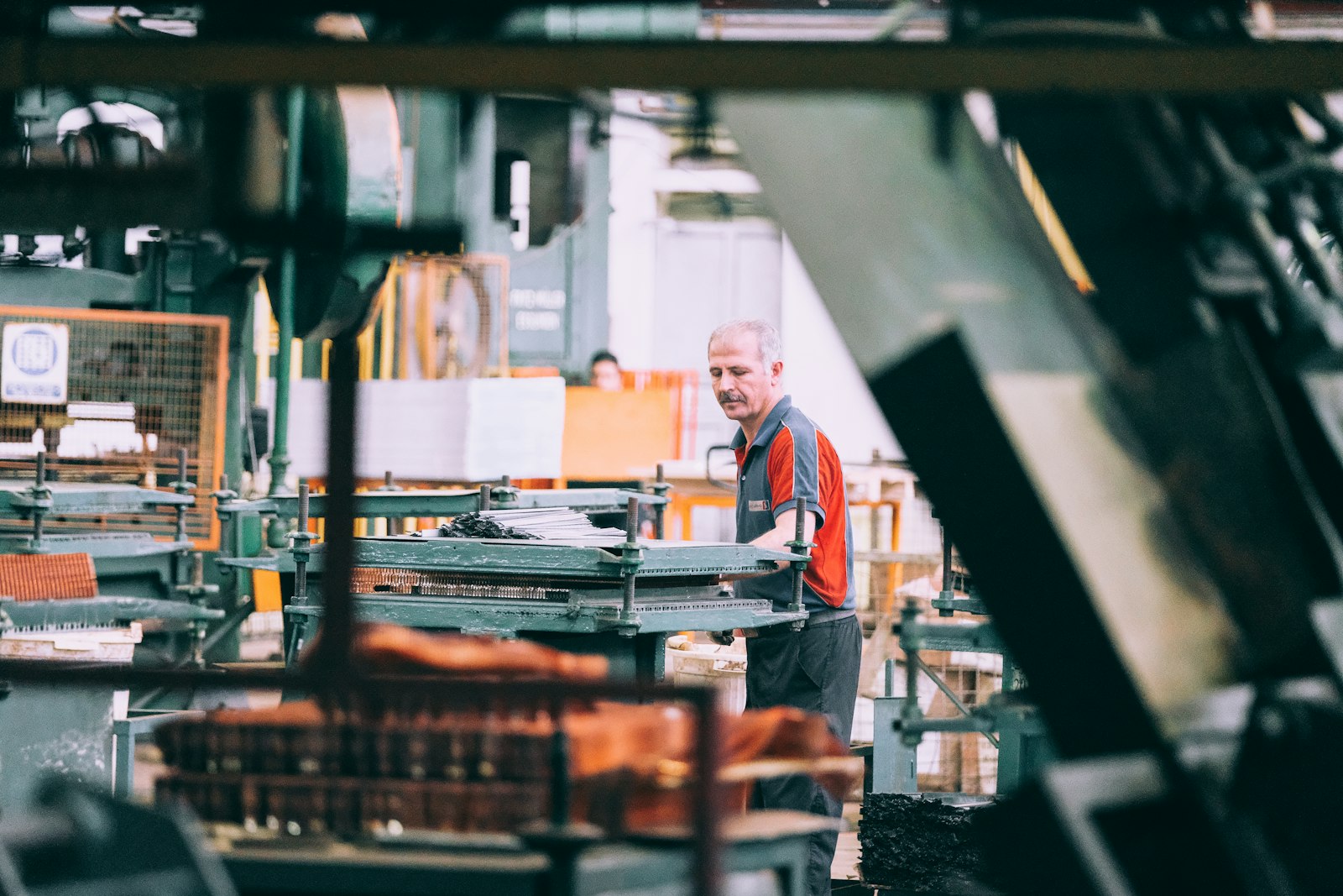 Operador industrial ajustando máquina na linha de produção de uma fábrica