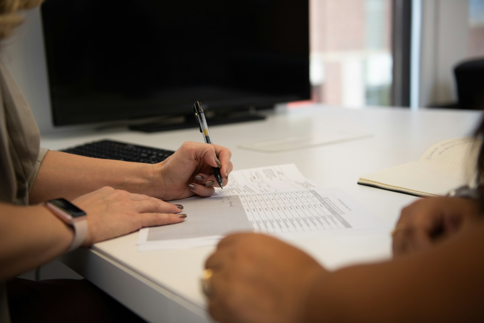 Duas pessoas conferindo lançamentos financeiros e papelada sobre a mesa
