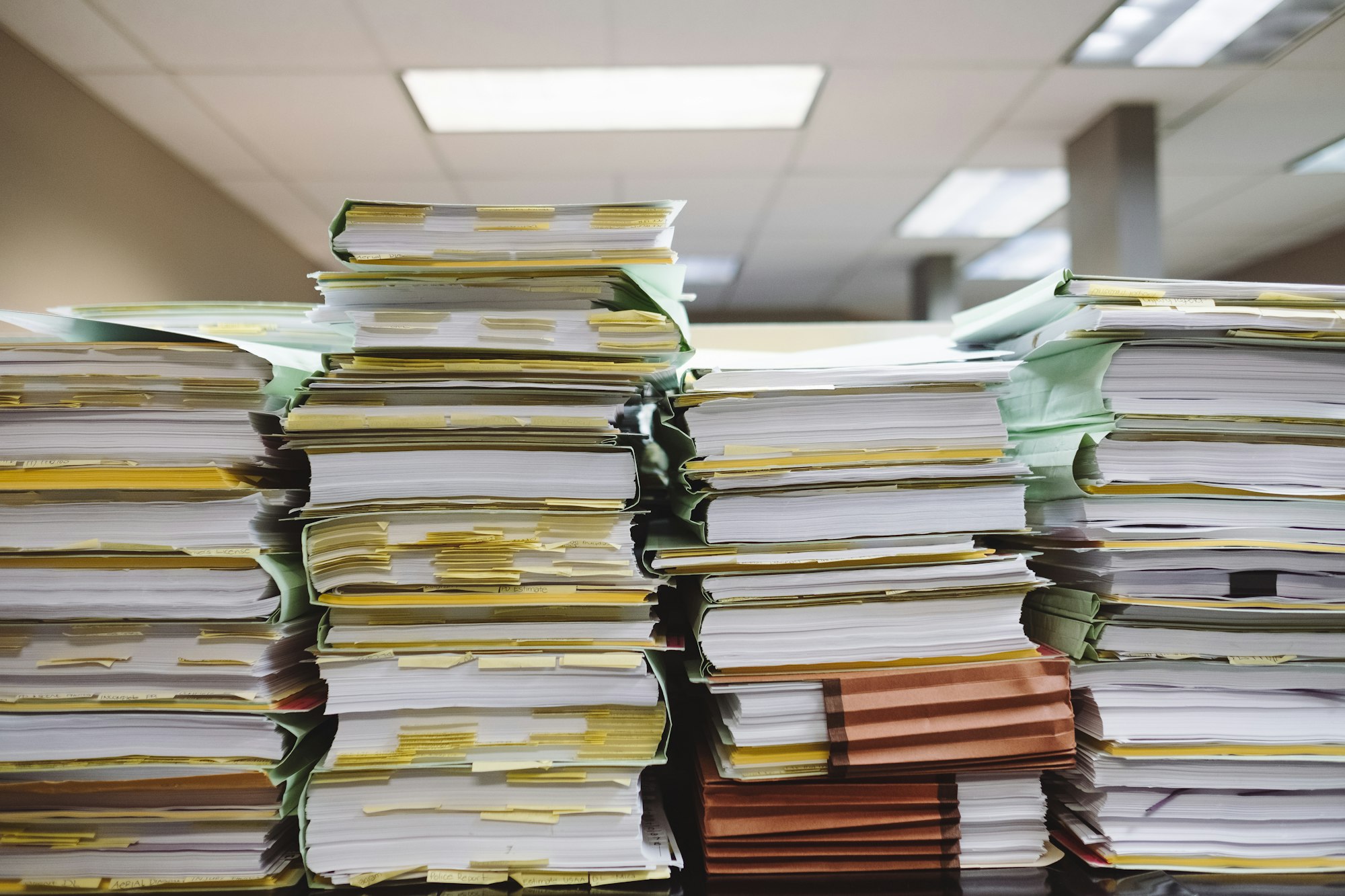 Pilhas de documentos e pastas representando o trabalho operacional acumulado na empresa