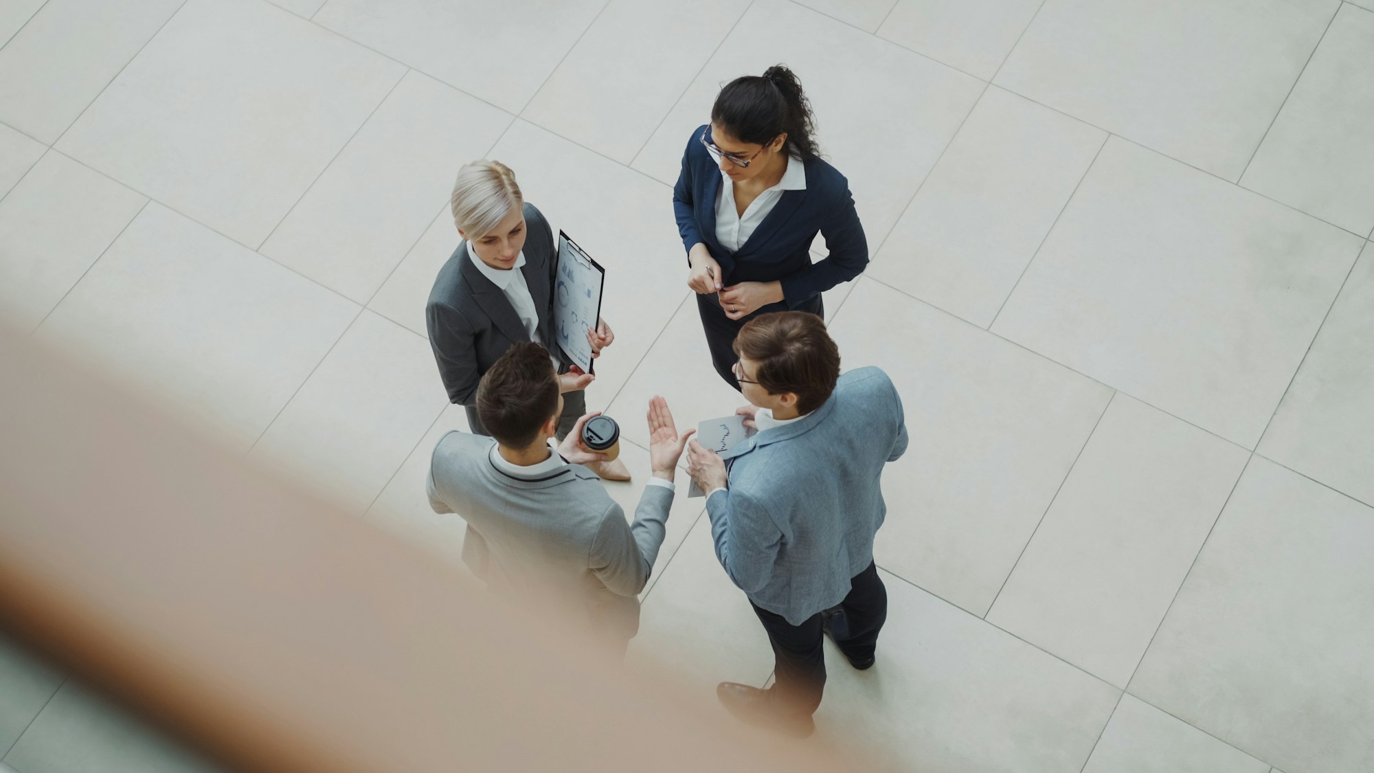 Quatro profissionais conversando no lobby de um escritório moderno, discutindo qual ferramenta de IA adotar