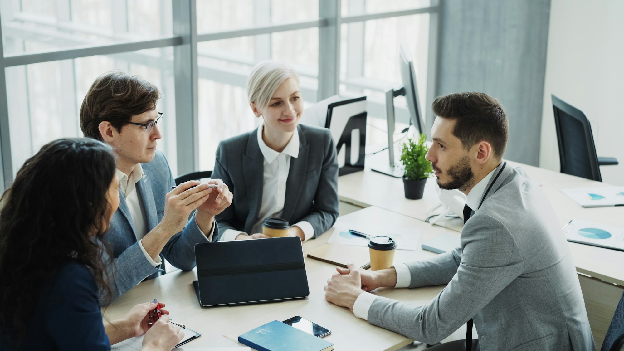 Equipe diversa colaborando em escritório moderno, representando empresas que adotaram o Claude no trabalho
